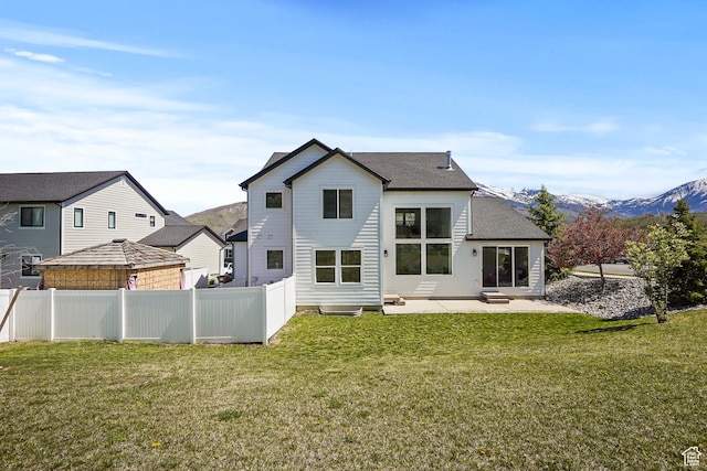 back of property with a patio area, a mountain view, and a shingled roof