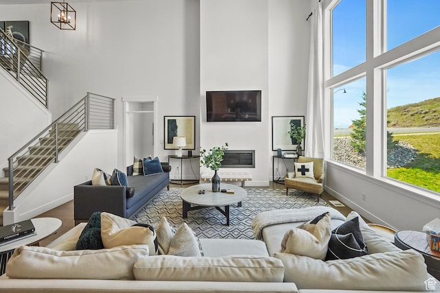 living room featuring a high ceiling, baseboards, stairs, and wood finished floors