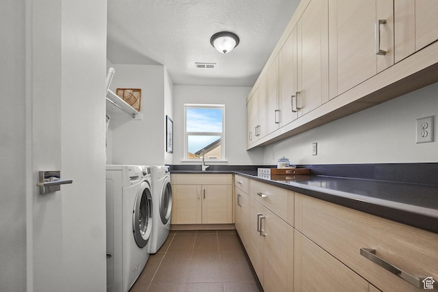 clothes washing area with washer and clothes dryer, dark tile patterned floors, a textured ceiling, and cabinet space