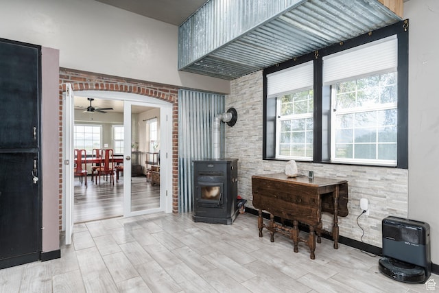 sitting room featuring a wood stove, a ceiling fan, wood finished floors, and heating unit