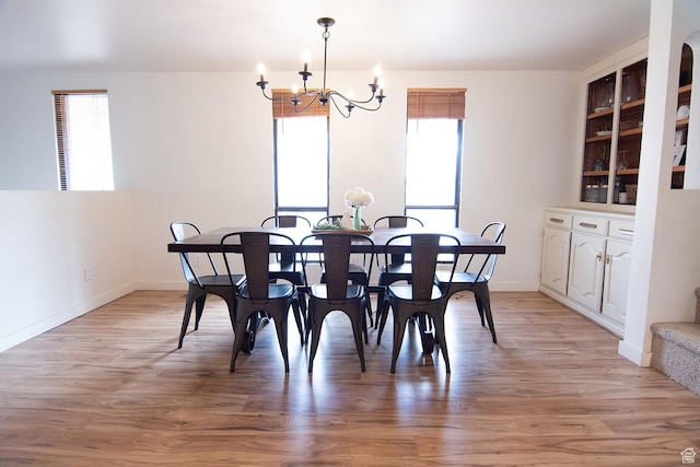 dining area featuring healthy amount of natural light, a chandelier, light wood finished floors, and baseboards