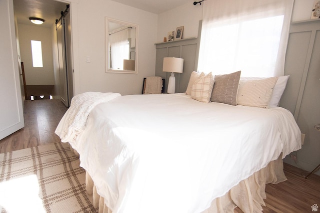 bedroom with wood finished floors and a barn door