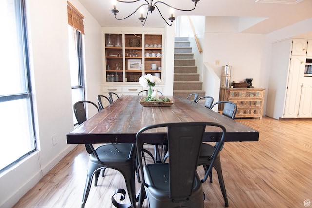dining space with a chandelier, stairway, and light wood finished floors