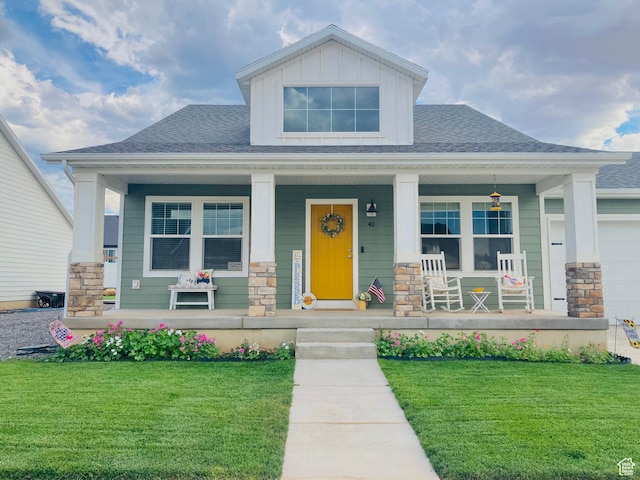 craftsman-style house featuring a porch, stone siding, a front yard, and a shingled roof