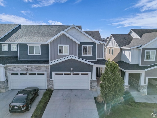 view of front of property featuring stone siding, board and batten siding, an attached garage, and concrete driveway