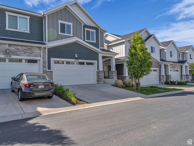 view of front of property featuring stone siding, board and batten siding, an attached garage, and concrete driveway