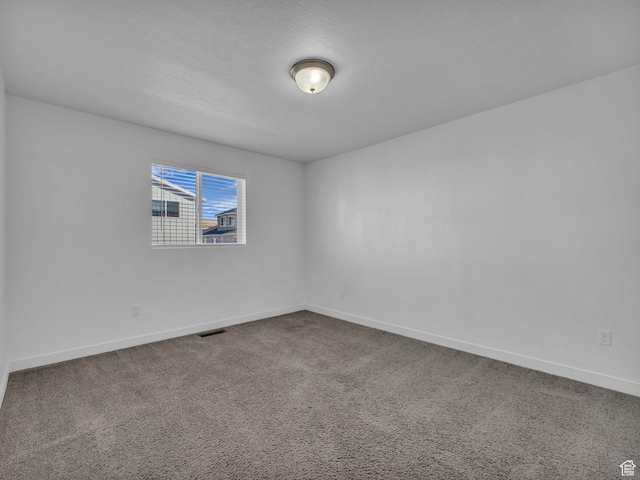 unfurnished room featuring baseboards and dark carpet