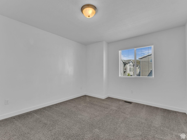 empty room with baseboards and dark colored carpet