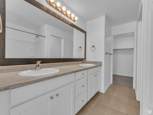 full bathroom featuring double vanity, a spacious closet, baseboards, and tile patterned flooring