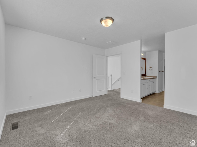 unfurnished bedroom with carpet floors, baseboards, and connected bathroom