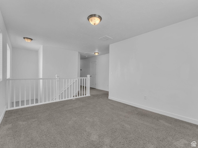 unfurnished room featuring carpet, baseboards, and attic access