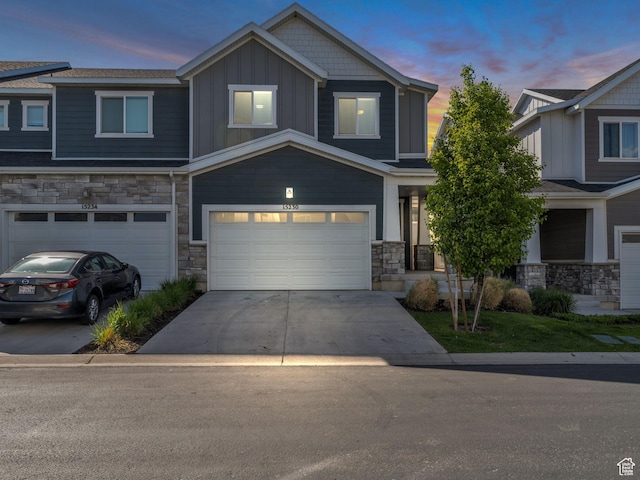 craftsman-style house featuring stone siding, an attached garage, board and batten siding, and concrete driveway
