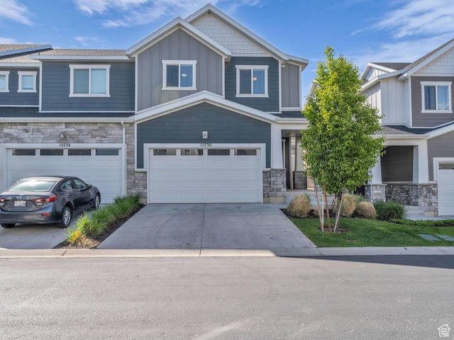 craftsman house with stone siding, an attached garage, concrete driveway, and board and batten siding