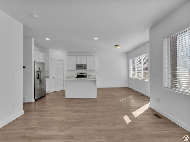 kitchen featuring appliances with stainless steel finishes, white cabinetry, open floor plan, recessed lighting, and baseboards