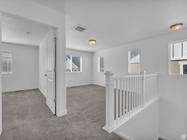 hall featuring carpet floors, an upstairs landing, and baseboards