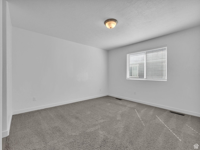 carpeted empty room with baseboards and a textured ceiling