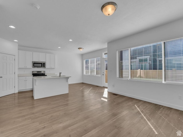 kitchen featuring appliances with stainless steel finishes, a sink, baseboards, white cabinetry, and recessed lighting