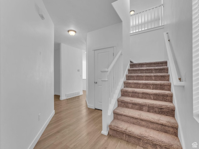 staircase featuring wood finished floors and baseboards