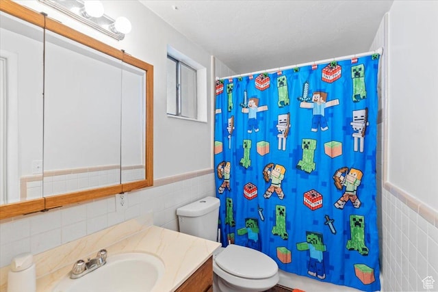 full bath featuring tile walls, toilet, curtained shower, vanity, and a wainscoted wall