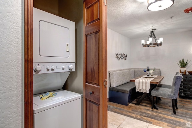 3000 Canyons Resort Dr Unit 3716, Park City, UT 84098 - laundry room with stacked washing machine and dryer, a chandelier, light wood finished floors, a textured ceiling, and a textured wall