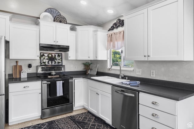kitchen featuring stainless steel appliances, a sink, under cabinet range hood, dark countertops, and white cabinetry