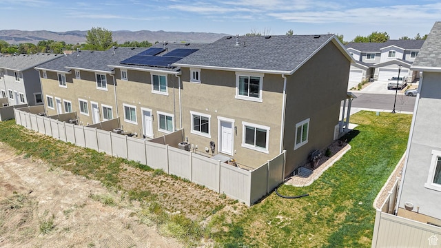 rear view of house featuring stucco siding, a residential view, fence, and a mountain view