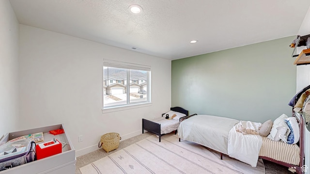 bedroom with light colored carpet, baseboards, recessed lighting, and a textured ceiling
