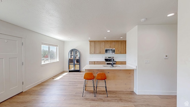 kitchen with appliances with stainless steel finishes, light wood-style floors, light countertops, baseboards, and recessed lighting