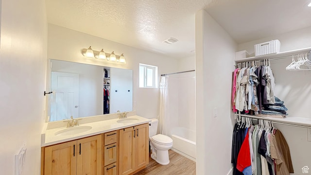 full bath with wood finished floors, double vanity, a walk in closet, toilet, and shower / bath combination with curtain
