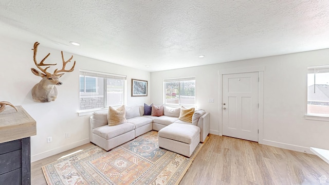 living room featuring healthy amount of natural light, light wood-style floors, a textured ceiling, recessed lighting, and baseboards