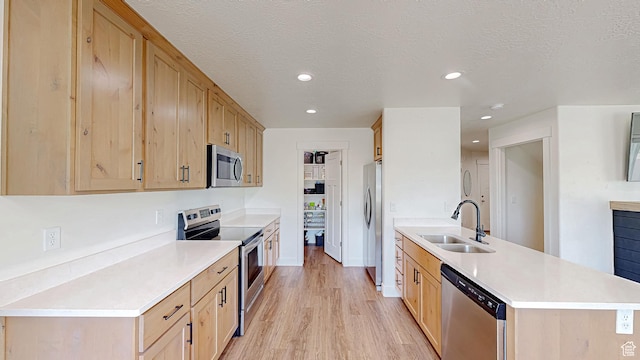 kitchen with appliances with stainless steel finishes, a sink, a peninsula, light brown cabinets, and recessed lighting