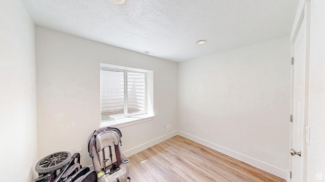 unfurnished office featuring light wood finished floors, baseboards, a textured ceiling, and recessed lighting