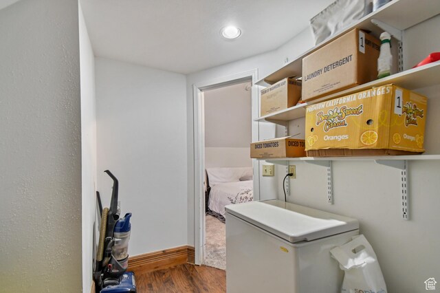 clothes washing area with wood finished floors and baseboards