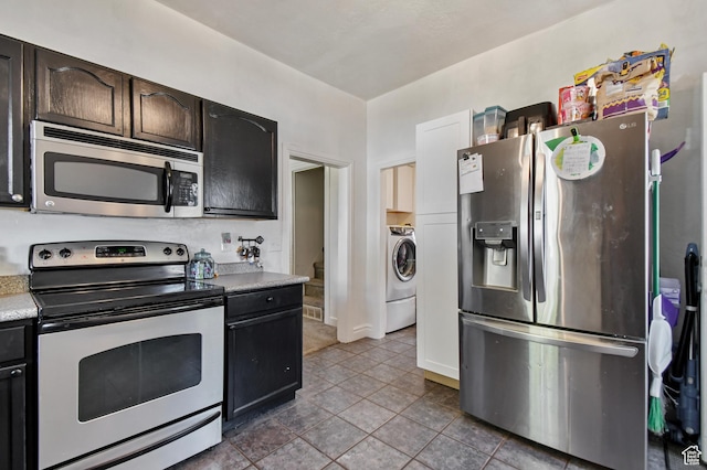 kitchen with appliances with stainless steel finishes, light countertops, washer / clothes dryer, tile patterned flooring, and dark brown cabinets