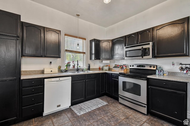 kitchen featuring appliances with stainless steel finishes, a sink, light countertops, and hanging light fixtures