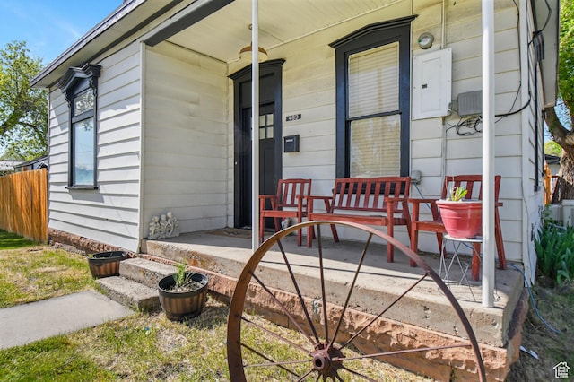 view of exterior entry with a porch and electric panel