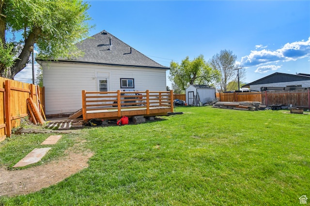 back of property with a deck, a storage unit, an outdoor structure, and roof with shingles