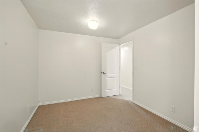 spare room with baseboards and light carpet