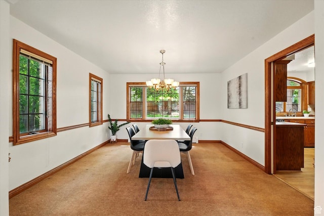 dining room featuring a chandelier, healthy amount of natural light, and baseboards