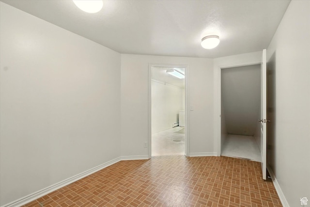 empty room with baseboards and brick patterned flooring