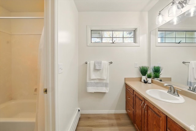 full bath featuring wood finished floors, vanity, a baseboard radiator, baseboards, and shower / bathtub combination with curtain