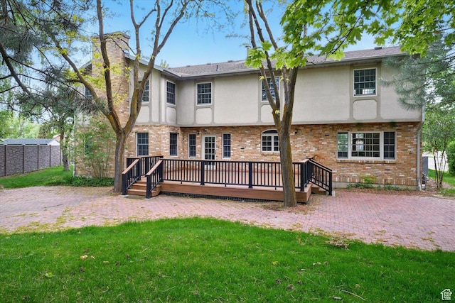 rear view of property featuring stucco siding, a wooden deck, a chimney, and brick siding