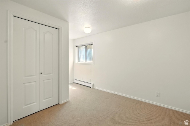 unfurnished bedroom with a baseboard radiator, light carpet, a closet, and baseboards