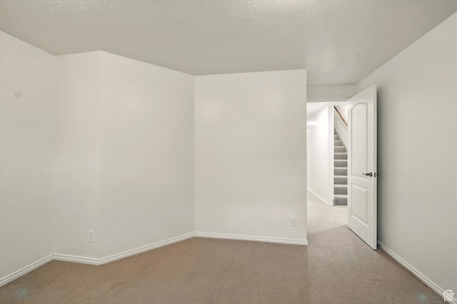 empty room featuring light colored carpet and baseboards