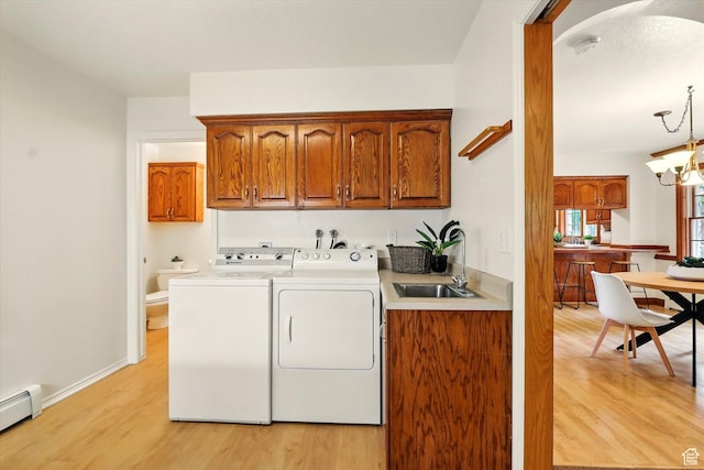laundry room with cabinet space, a baseboard radiator, washer and dryer, and light wood-type flooring