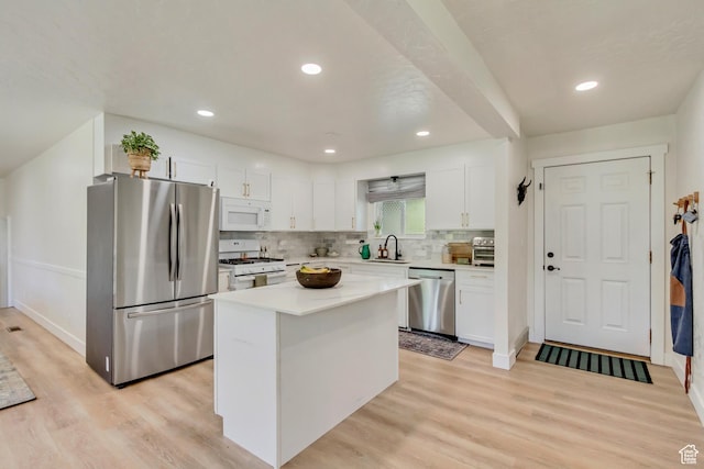 1145 S 350 W, Orem, UT 84058 - kitchen featuring stainless steel appliances, white cabinets, a kitchen island, light wood-type flooring, and decorative backsplash