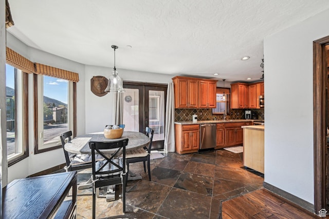 kitchen with dishwasher, backsplash, light countertops, pendant lighting, and baseboards