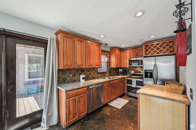 kitchen with stainless steel appliances, a sink, tasteful backsplash, brown cabinetry, and recessed lighting