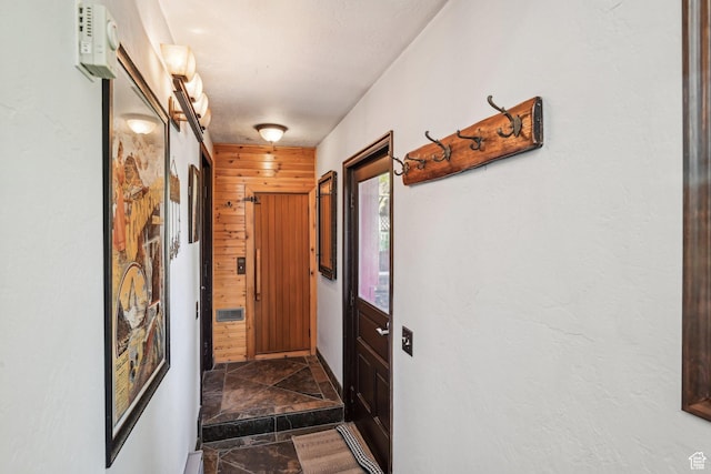 corridor featuring dark stone finish flooring and wooden walls