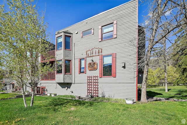 rear view of house featuring a yard and a balcony